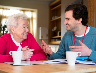 Older woman and younger man chatting over a cup of tea