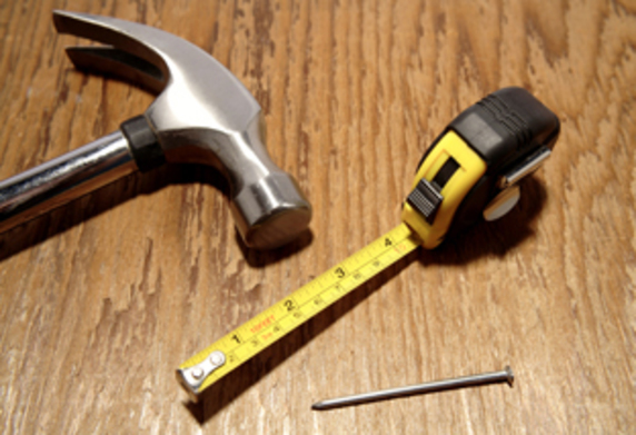 A photo of a hammer, measuring tape and nails
